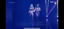 a couple of women are standing on a stage in front of a blue background .