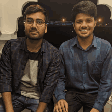 two men are sitting next to each other and smiling at the camera