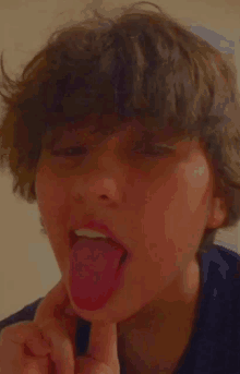 a young boy is sticking his tongue out and making a funny face