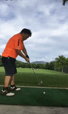 a man swings a golf club at a golf ball