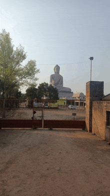 a large statue of buddha is behind a gate