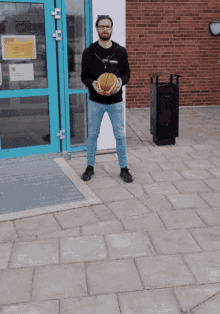 a man holding a basketball in front of a building that has a sign on it that says ' ambulance '