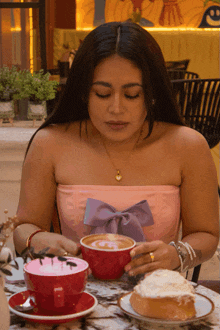 a woman sits at a table with a cup of coffee and a pastry