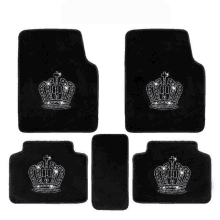 a set of four black car mats with a crown design on them