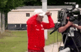 a man in a red jacket is standing in front of a camera with tvp sport written on the bottom