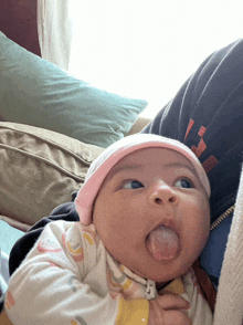 a baby wearing a pink hat is sticking out his tongue