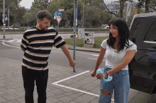 a man and a woman are holding hands in front of a street sign that says " a " on it