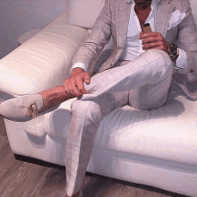 a man in a suit is sitting on a couch with his legs crossed