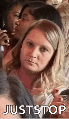 a woman is making a funny face while sitting in a crowd of people at a party .