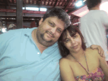 a man and a woman pose for a picture in front of coca cola signs