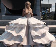 a woman in a wedding dress is standing in front of a statue