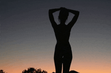 a silhouette of a naked woman with her hands on her head