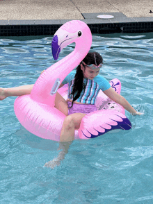 a girl is floating on a pink flamingo float in a pool