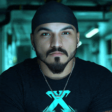 a man with a beard wearing a black shirt with a blue x on it