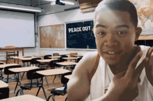 a boy in a classroom with a peace out sign on the wall