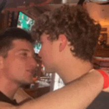 two young men are hugging and kissing in a restaurant .