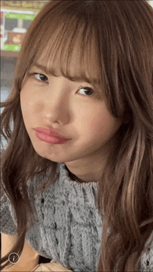 a close up of a woman 's face with a gray sweater on