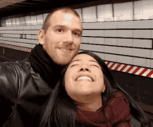 a man and a woman are posing for a picture in front of a sign that says ' a '