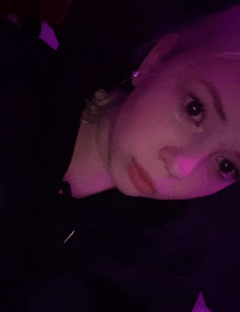 a close up of a person 's face with purple lights behind them