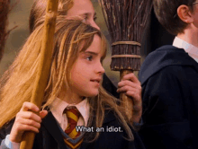 a girl in a harry potter outfit is holding a broom and saying what an idiot