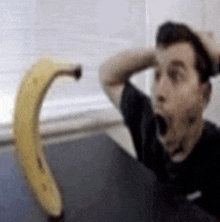 a man is yawning in front of a banana that is very large