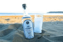 a bottle of alcohol and a glass of alcohol on a beach .