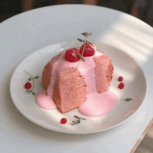 a piece of cake with pink frosting and raspberries on top on a plate .