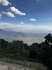 a fence surrounds a view of a valley and mountains