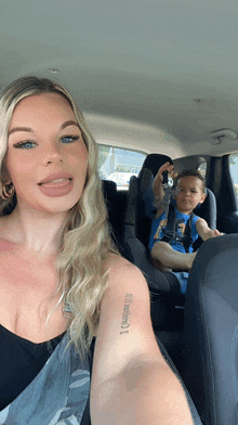 a woman is taking a selfie with a child in a car seat