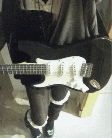 a person holding a black and white guitar