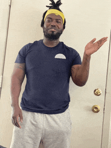 a man standing in front of a door wearing a headband and a blue shirt