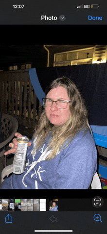 a woman wearing glasses is holding a can of soda in front of her face