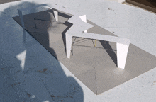 a model of a building with a shadow on the ground