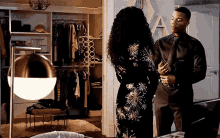 a man and a woman are standing next to each other in front of a closet .