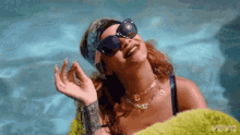 a woman wearing sunglasses is sitting in a swimming pool .