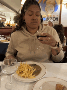 a woman sitting at a table holding a glass of wine in front of a poster that says bisson