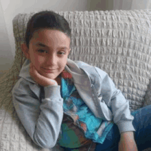 a young boy is sitting on a couch with his hand on his face .