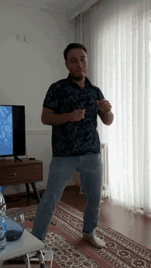 a man in a blue shirt is dancing in front of a tv