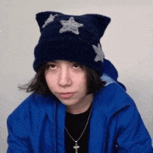 a young girl wearing a blue jacket and a blue hat with stars on it