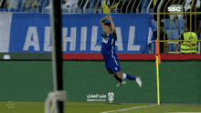 a soccer player jumps in the air in front of a sign that says al hilal