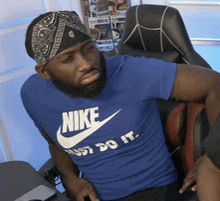 a man wearing a blue nike t-shirt is sitting in a chair