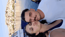 a man and a woman are posing for a picture in front of a harbor