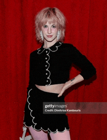 a woman with pink hair is standing in front of a red curtain with the caption gettyimages credited to dimitrios kambouris