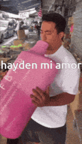 a man in a white shirt is holding a pink container that says hayden mi amor on it