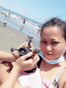 a woman wearing a mask holds a small dog in her arms