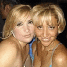 two blonde women are posing for a picture and smiling for the camera .