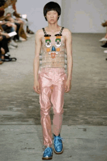 a model walks down the runway at a fashion show wearing a shirt that looks like a face