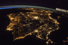 an aerial view of the earth at night with a satellite in the foreground