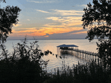 a sunset over a body of water with a dock in the middle