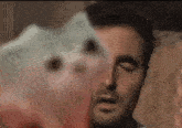 a close up of a man 's face with a piggy bank in the foreground .